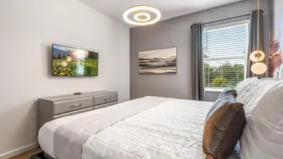 a bedroom with a white bed and a window at Luxury Home: Pool, Theater, Near Disney in Kissimmee
