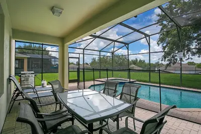 a patio with a table and chairs and a swimming pool at Highland View 6BR Villa Private Pool Near Disney in Orlando
