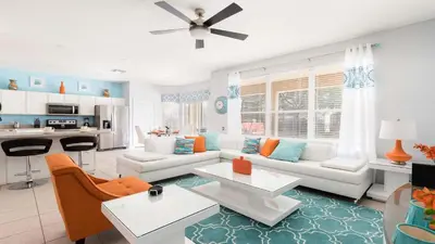a living room with a white couch and orange chairs at Windsor Hill 6BR South-facing Pool/Spa Near Disney in Orlando