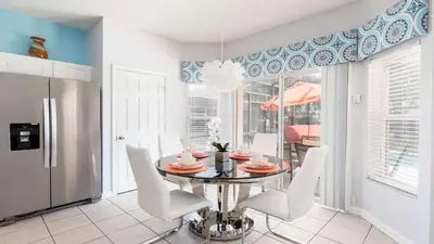 a dining room with a table and white chairs at Windsor Hill 6BR South-facing Pool/Spa Near Disney in Orlando