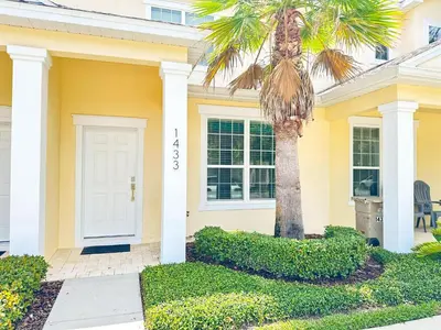 a yellow house with a palm tree in front of it at 3 bedrooms pool home Retreat Close to Disney in Orlando