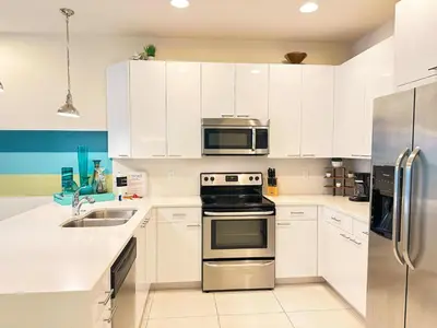 a kitchen with white cabinets and stainless steel appliances at 3 bedrooms pool home Retreat Close to Disney in Orlando