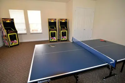 a ping pong table in a room with four video games at 3 bedrooms pool home Retreat Close to Disney in Orlando