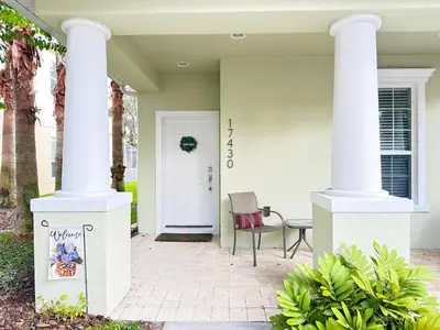 a porch with two white columns and a chair at Affordable Disney pool home 3 Bed 3 bath in Orlando