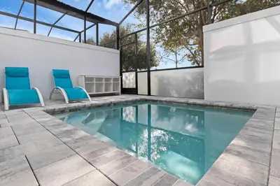 a swimming pool with two blue chairs next to a building at 3 bedrooms pool home Hidden Forest Resort Amenities in Orlando