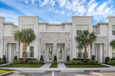 a white house with palm trees in front of it at 3 bedrooms pool home Hidden Forest Resort Amenities in Orlando
