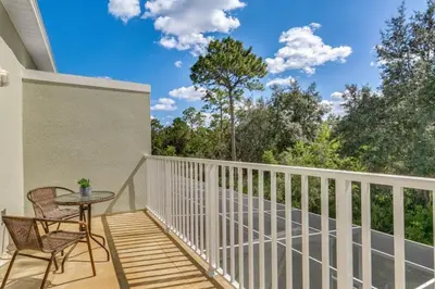 a balcony with a table and chairs and trees at 3 bedrooms pool home with clubhouse amenities Retreat in Orlando