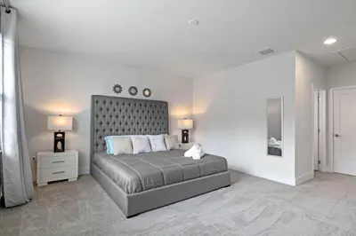a bedroom with a bed and two lamps and a mirror at 3 bedrooms pool home Hidden Forest Resort Amenities in Orlando