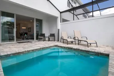 a swimming pool with two chairs next to a house at 3 bedrooms pool home Hidden Forest Resort Amenities in Orlando