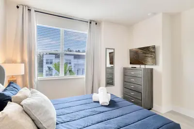 a bedroom with a blue bed and a window at 4 bedrooms pool home Hidden Forest Resort Amenities in Orlando
