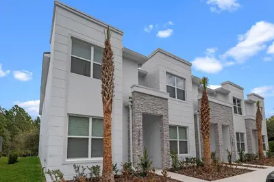 a white house with palm trees in front of it at 3 bedrooms pool home Hidden Forest Resort Amenities in Orlando