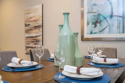 a table with a green vase and plates and wine glasses at Gorgeous 4 Suites DREAM Villa 5 min to Disney in Orlando