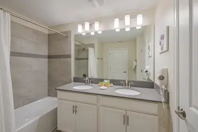 a bathroom with two sinks and a tub and a mirror at Magical Retreat, Spacious villa 10 min from Disney in Kissimmee