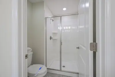 a white bathroom with a shower and a toilet at Magical Retreat, Spacious villa 10 min from Disney in Kissimmee