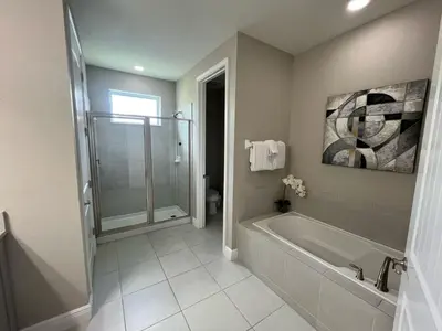 a bathroom with a shower and a tub and a toilet at Luxury 6 BR 6 Bath @Encore Resort Pool Spa Grill. in Orlando