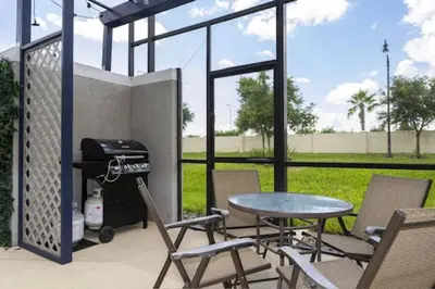 a patio with a table and chairs and a grill at Amazing Unbeatable Experience Themed Home w/ Private Pool and Resort in Kissimmee