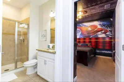 a bathroom with a toilet and a painting on the wall at Amazing Unbeatable Experience Themed Home w/ Private Pool and Resort in Kissimmee