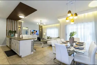 a kitchen and living room with a table and white chairs at Amazing Unbeatable Experience Themed Home w/ Private Pool and Resort in Kissimmee