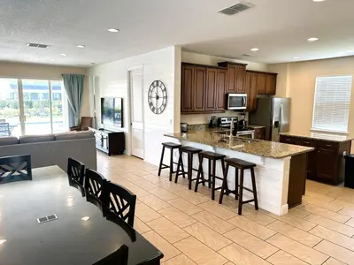 a kitchen with a counter and bar with stools in it at 6 bedrooms pool home Encore Reunion Resort Gated in Orlando