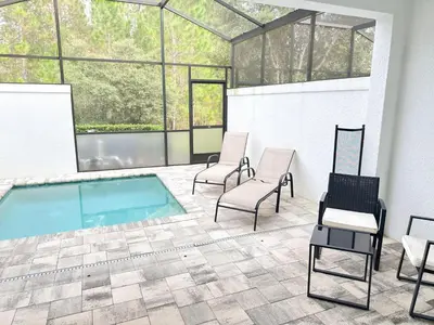 a patio with a pool and two chairs and a swimming pool at 3 bedrooms pool home Hidden Forest Resort Amenities in Orlando