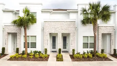 a white house with palm trees in front of it at 3 bedrooms pool home Hidden Forest Resort Amenities in Orlando