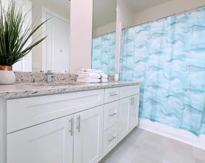 a white bathroom with a blue shower curtain at Brand New 3 Suites 5 min to Disney in Orlando