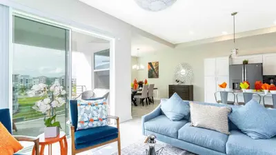 a living room with a blue couch and a kitchen at Strategic Condo 2 Bd Close to Disney Storey Lake in Kissimmee