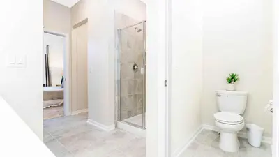 a white bathroom with a shower and a toilet at Strategic Condo 2 Bd Close to Disney Storey Lake in Kissimmee