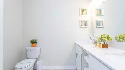 a white bathroom with a toilet and a sink at Strategic Condo 2 Bd Close to Disney Storey Lake in Kissimmee