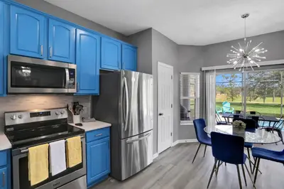a kitchen with blue cabinets and a table with chairs at Themed Luxury 6BR Getaway with Resort Amenities in Orlando