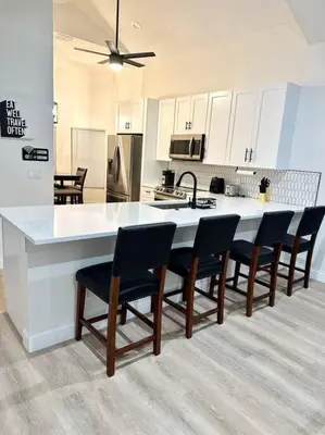 a kitchen with a large white counter and chairs at Superhost FREE Heated Pool 9 minutes to MCO 15 minutes to Disney in Kissimmee