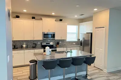 a kitchen with white cabinets and a island with bar stools at Wonderful home close to disney & universal in Kissimmee