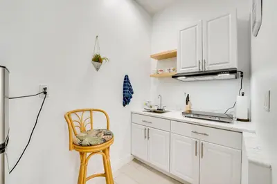 a kitchen with white cabinets and a wooden chair at 3 Mi to Lakefront Beach St Cloud Apt in Ashton