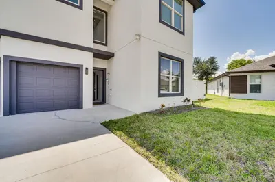a white house with a driveway and a garage at 3 Mi to Lakefront Beach St Cloud Apt in Ashton