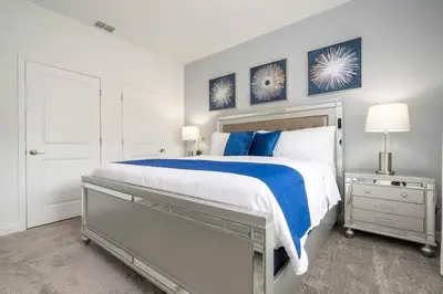 a white bedroom with a large bed with blue pillows at Fantastic 4 Bd w Pool at Storey Lake Resort 2709 in Kissimmee