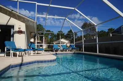 a large swimming pool with blue chairs at Christine's Villa in Kissimmee