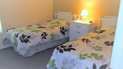 a bedroom with two beds and a dresser with a bedskirts at Christine's Villa in Kissimmee
