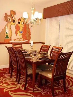 a dining room table and chairs with a painting of dogs at Princess Hideaway in Orlando
