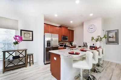 a kitchen with a counter and a kitchen island with chairs at Stunning Storey Lake Villa Prime Location in Kissimmee