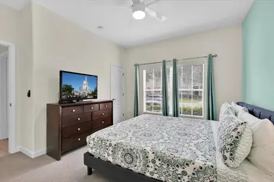 a bedroom with a bed and a dresser with a tv at Lake View 4 Bedroom Pool Home in Kissimmee