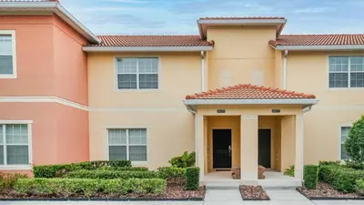 a house with bushes and trees in front of it at Lake View 4 Bedroom Pool Home in Kissimmee