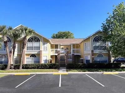 a large yellow house with palm trees in a parking lot at Cozivill in Kissimmee