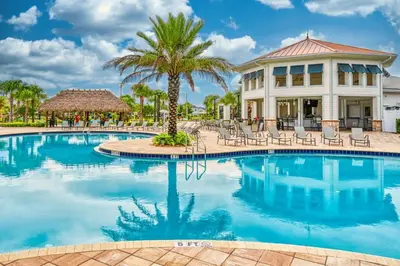 a resort pool with chairs and a palm tree at Private Pool Prime Location Beautiful Home in Kissimmee