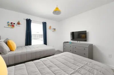 a bedroom with two beds and a tv and a dresser at Charming Mickey-Themed Home Prime Location in Kissimmee