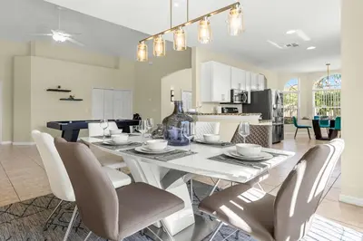 a dining room and kitchen with a white table and chairs at Luxury 4BR Home - Private Pool BBQ - Near Disney in Kissimmee