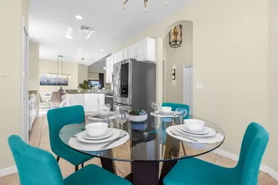 a dining room with a glass table and blue chairs at Luxury 4BR Home - Private Pool BBQ - Near Disney in Kissimmee