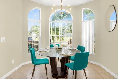 a dining room with a round table and blue chairs at Luxury 4BR Home - Private Pool BBQ - Near Disney in Kissimmee