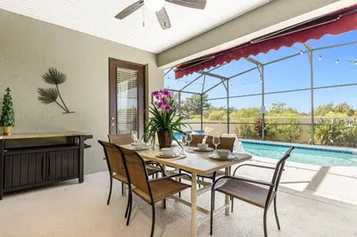 a dining room with a table and chairs and a pool at Luxury 4BR Home - Private Pool BBQ - Near Disney in Kissimmee