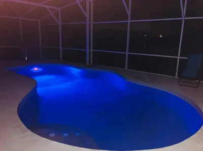 a large blue swimming pool in a room at night at Luxury Waterfront 3b2b Heated Pool , Game Room , Piano House in Kissimmee