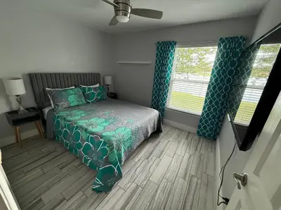 a bedroom with a bed and two windows at Luxury Waterfront 3b2b Heated Pool , Game Room , Piano House in Kissimmee